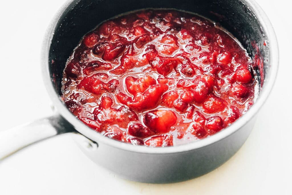 A pot filled with cooked homemade cranberry sauce ingredients 