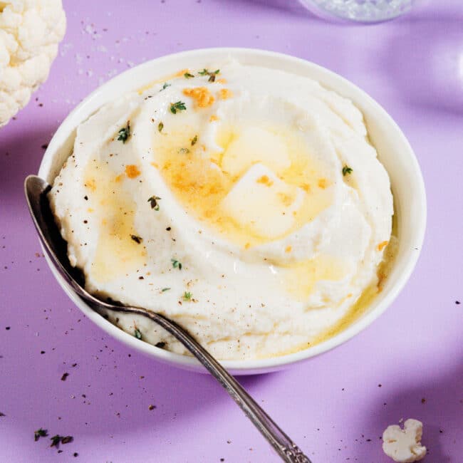 Mashed cauliflower in a bowl with a spoon.