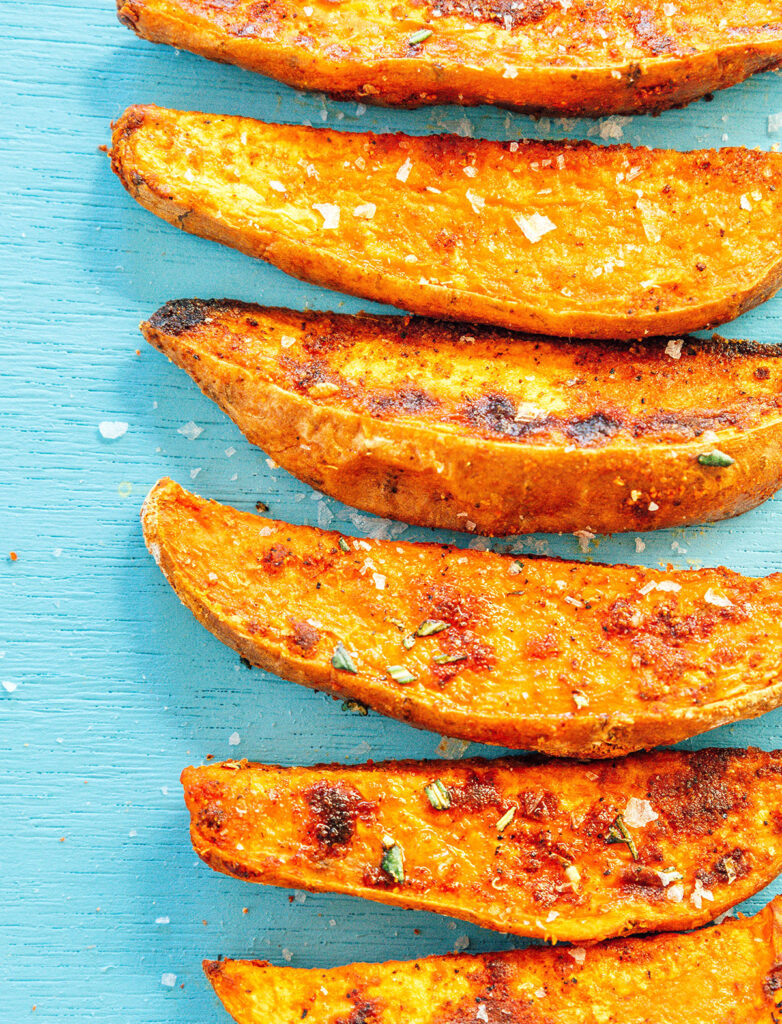A close up view detailing the textures and seasonings of oven-baked sweet potato wedges