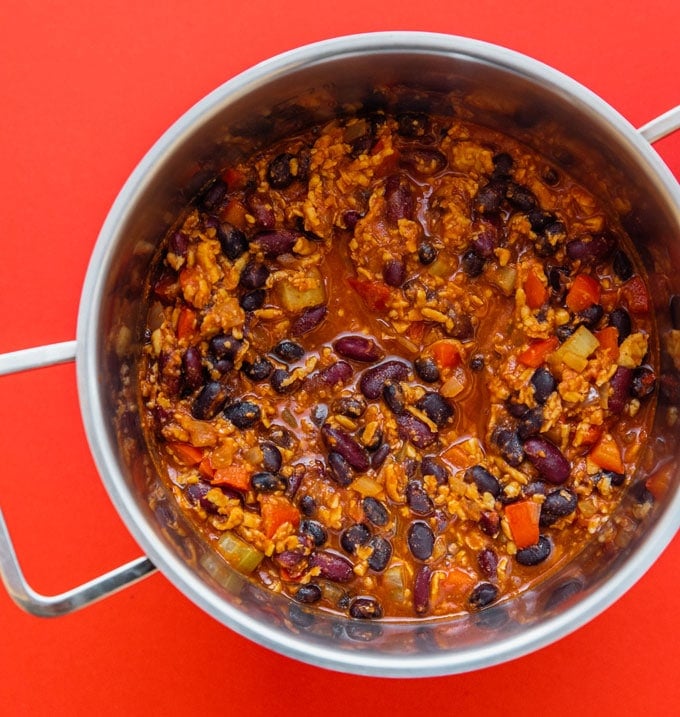 Vegan tempeh chili in a pot on a red background