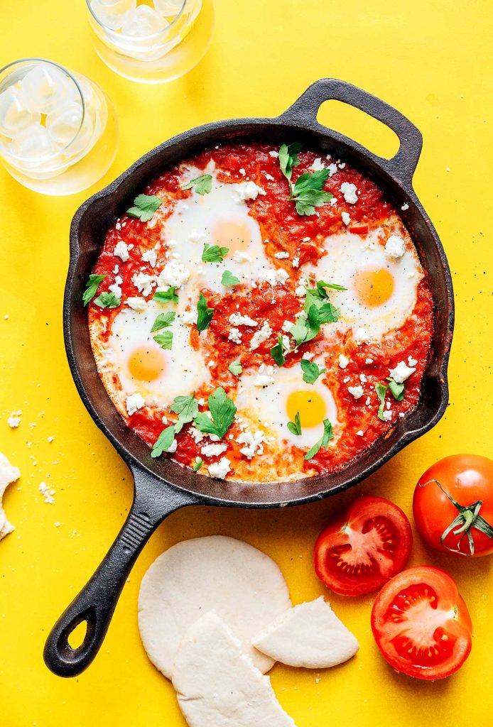 Shakshuka in a cast iron skillet on a yellow background
