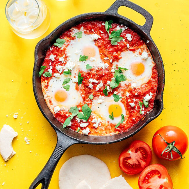 Shakshuka in a cast iron skillet on a yellow background