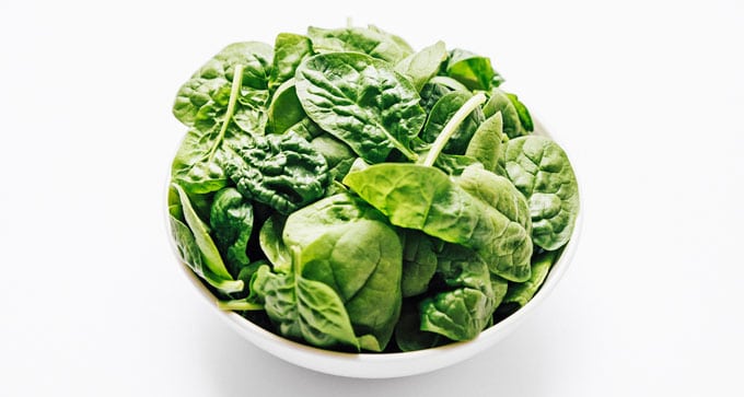 Spinach leaves in a bowl on a white background