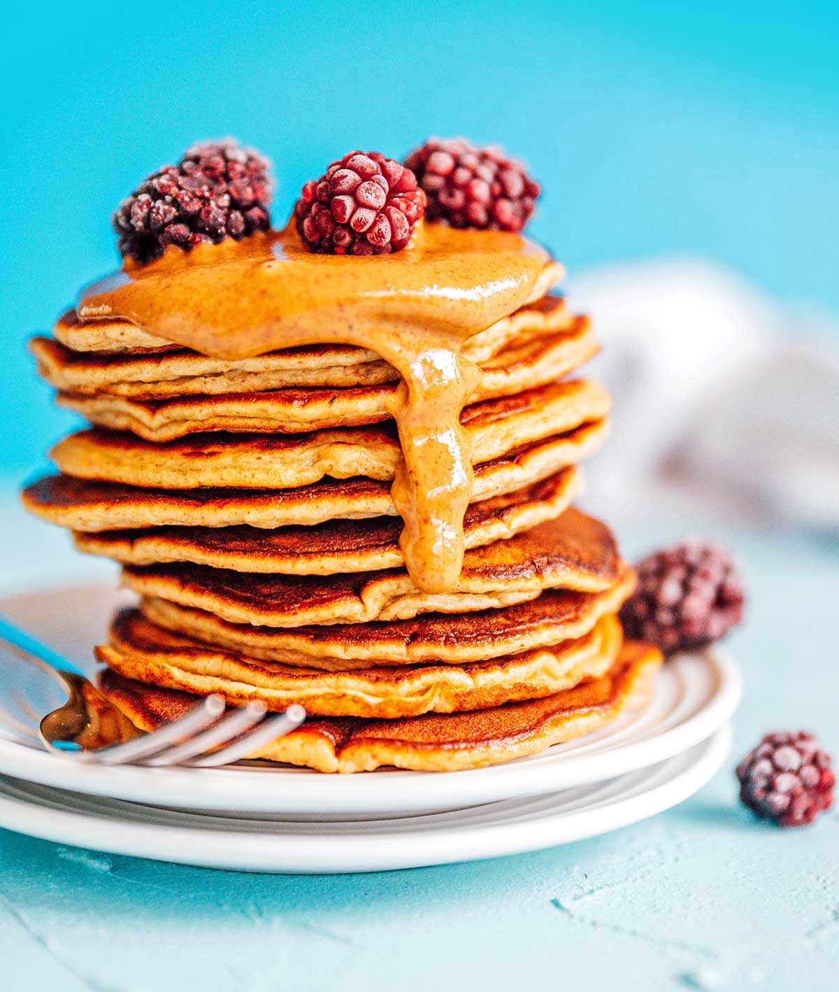 Paleo pancakes with almond butter and berries on a blue background