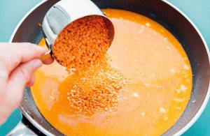 Lentils being poured into the curry sauce.