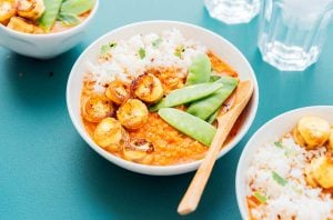 A bowl of banana curry with rice and peas.