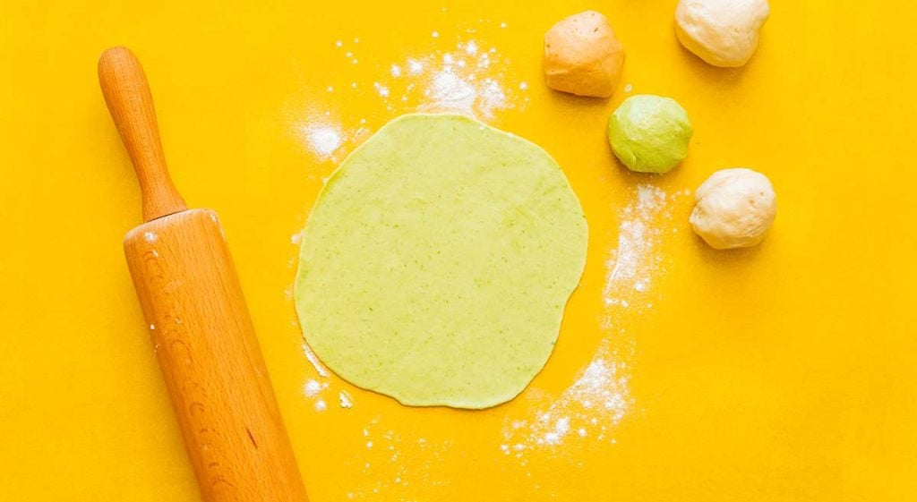 Rolling out a green tortillas with a rolling pin