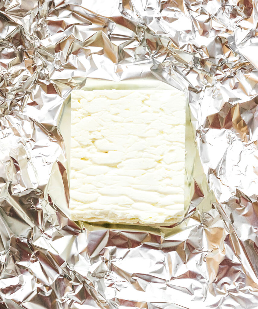 A piece of tinfoil with a block of feta sitting on top