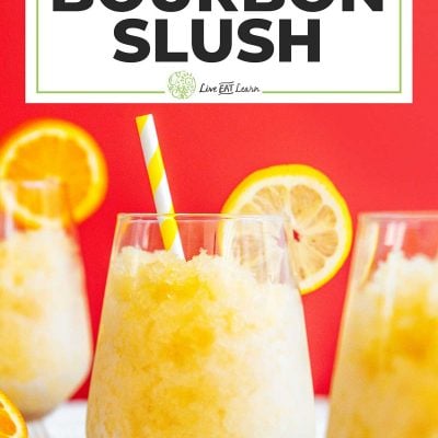 Bourbon slush in a glass with a straw on a red background