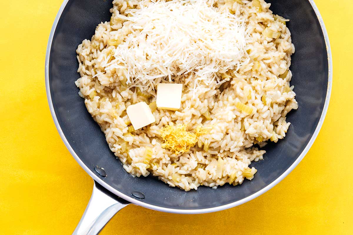 Adding butter and cheese to a pan of risotto
