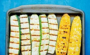 Char grilled zucchini and corn on a baking sheet