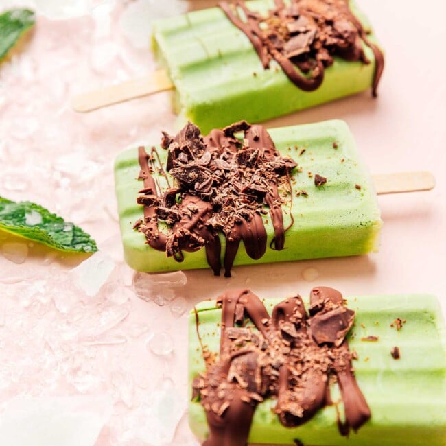 Green mint chocolate popsicles on a pink background