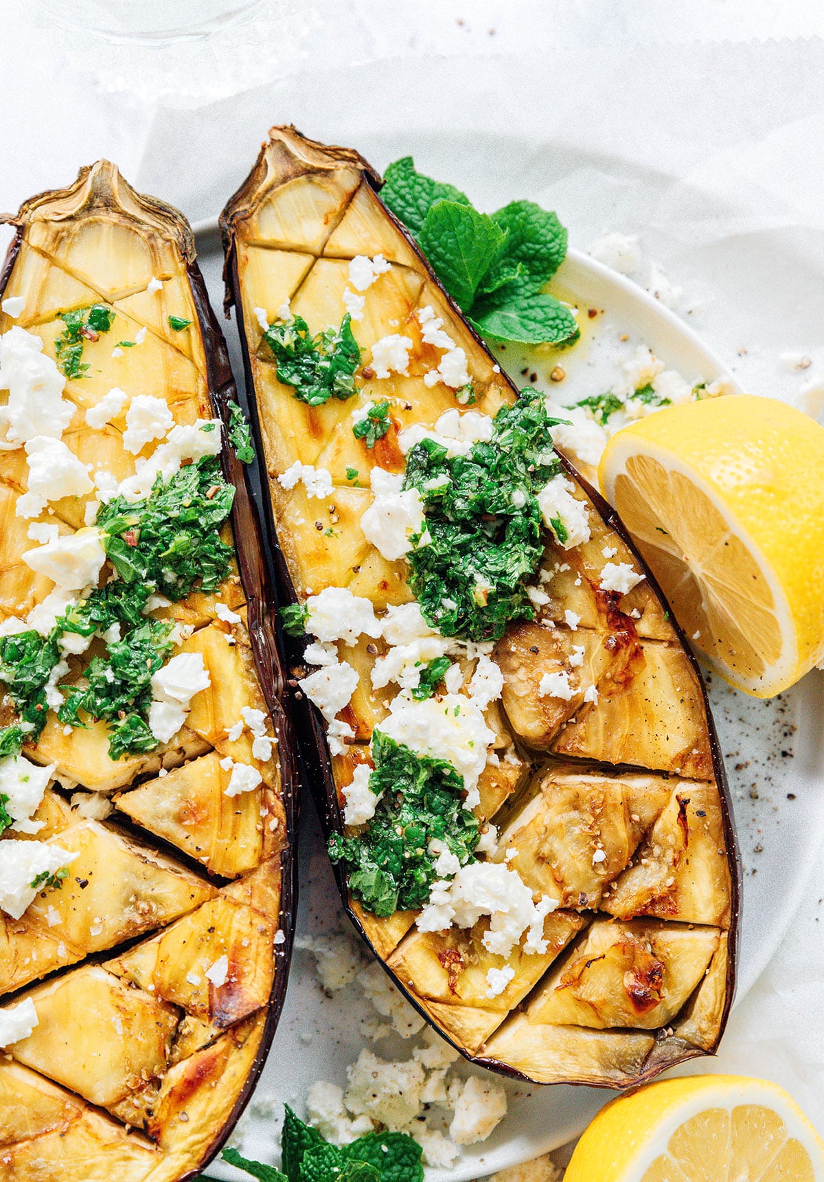 Roasted eggplant cut open with feta and mint.