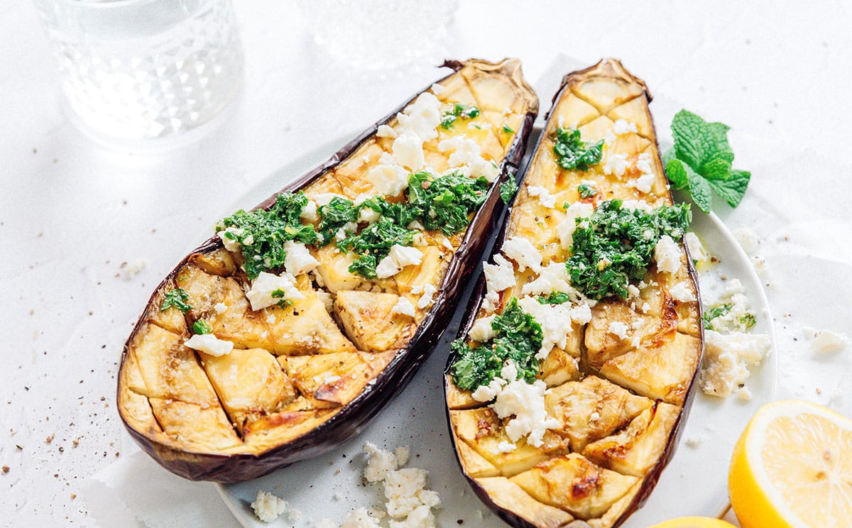 Roasted eggplant cut open with feta and mint.