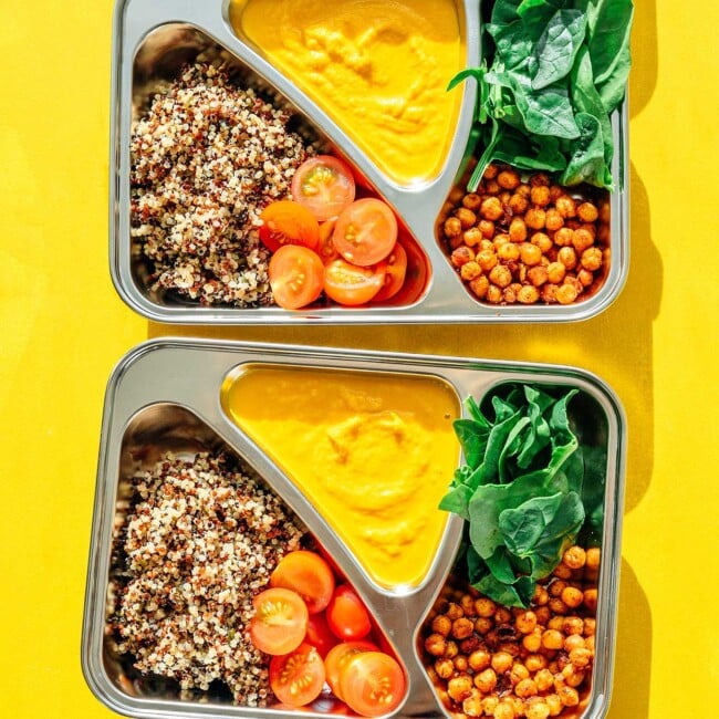 Vegetarian meal prep with roasted chickpeas, quinoa, yellow sauce, and spinach on a yellow background