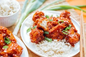 General Tso's cauliflower on a plate with rice and green onions