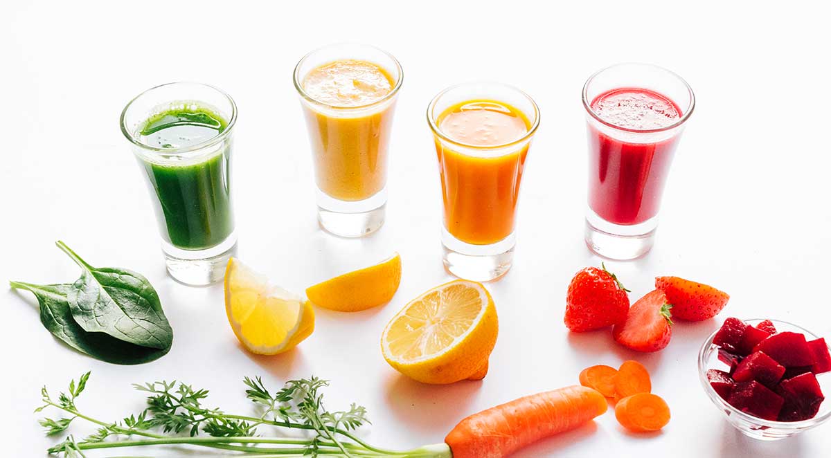 Rainbow smoothie shots with fruits and veggies on a white background