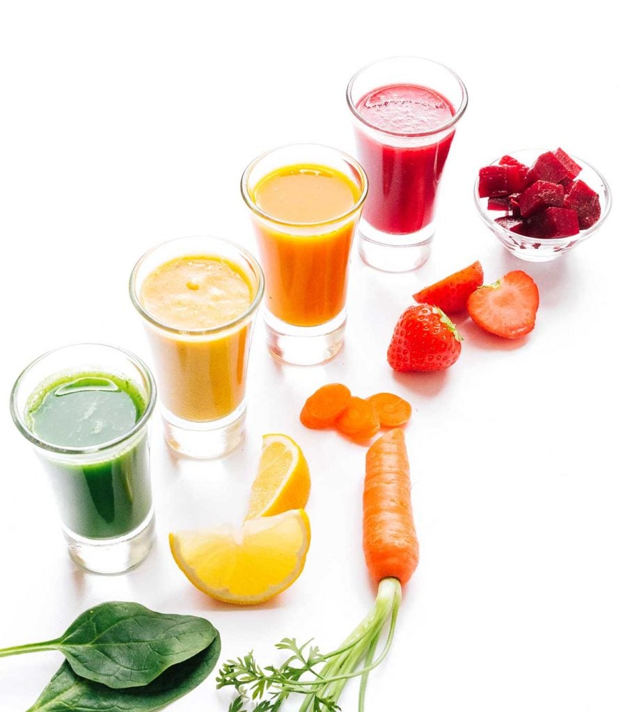 Rainbow smoothie shots with fruits and veggies on a white background