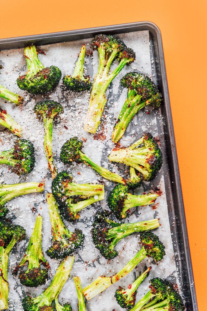 Roasted broccoli laid out on baking sheet after being baked.
