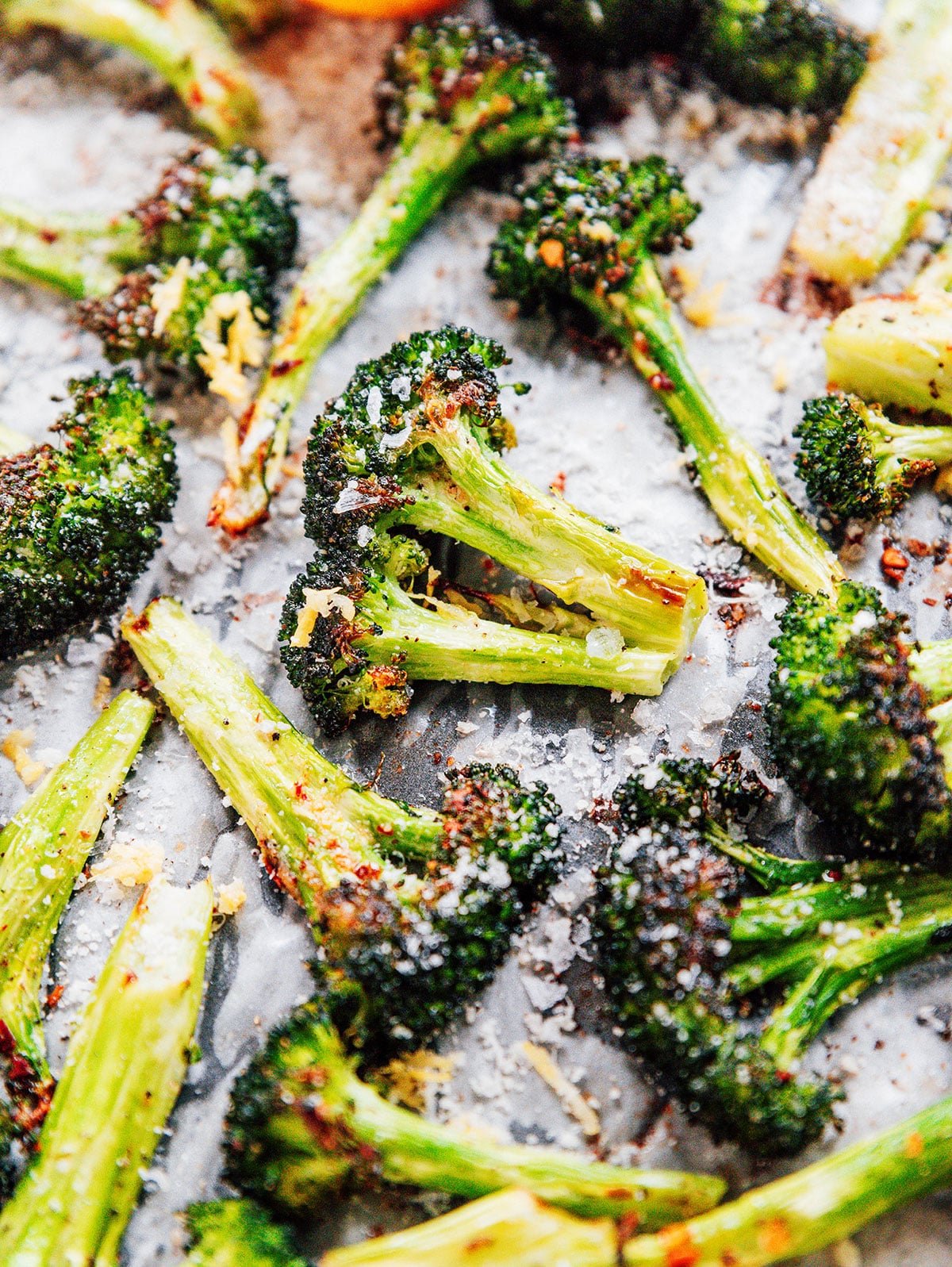 Close up of roasted broccoli on a sheet pan with spices and salt all over.