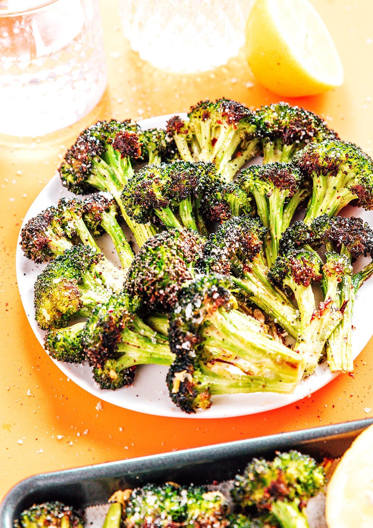 Roasted Broccoli on a plate with lemon slice behind it.