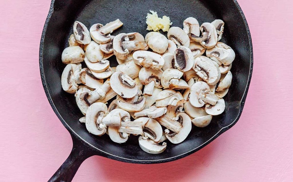 A cast iron skillet filled with sliced mushrooms