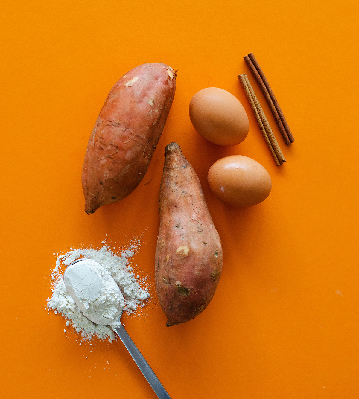 Ingredients for sweet potato cinnamon rolls on an orange background.