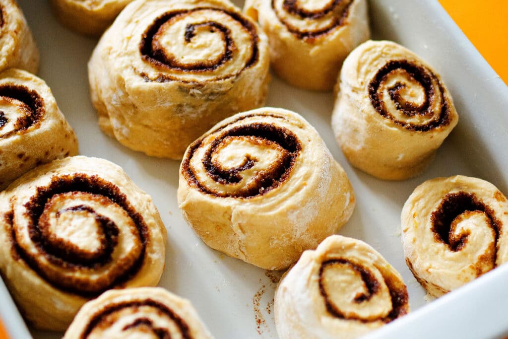 Raw cinnamon rolls in a baking dish.