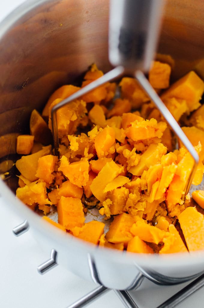 Mashing sweet potatoes in a bowl - Need a healthy cookie recipe that's just as moist and delicious as your old favorites? This Sweet Potato Cookie recipe with chocolate and oats has you covered.