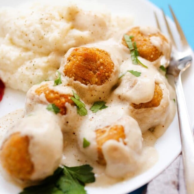 These Swedish Quinoa Meatballs are a healthy combination or quinoa and cauliflower, smothered in simple cream sauce and served atop fluffy mashed cauliflower! No need to go furniture shopping to have a taste of Sweden.