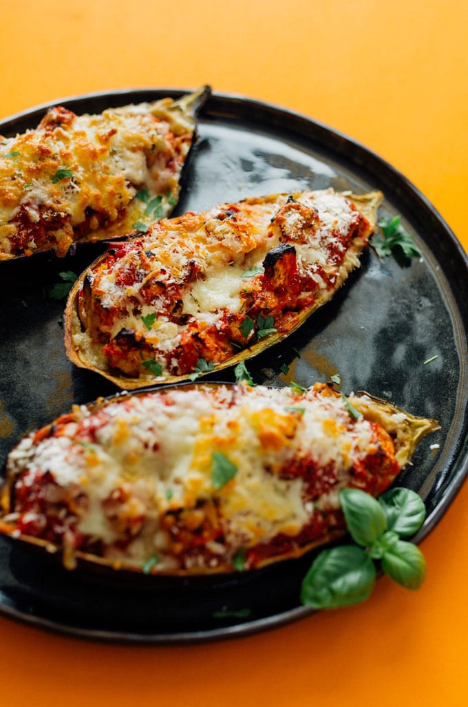 Stuffed eggplant parmesan on a plate with an orange background