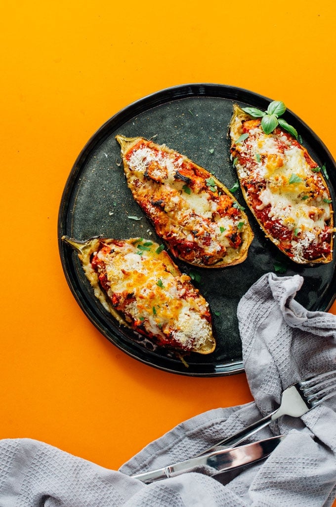Stuffed eggplant parmesan on a plate with an orange background