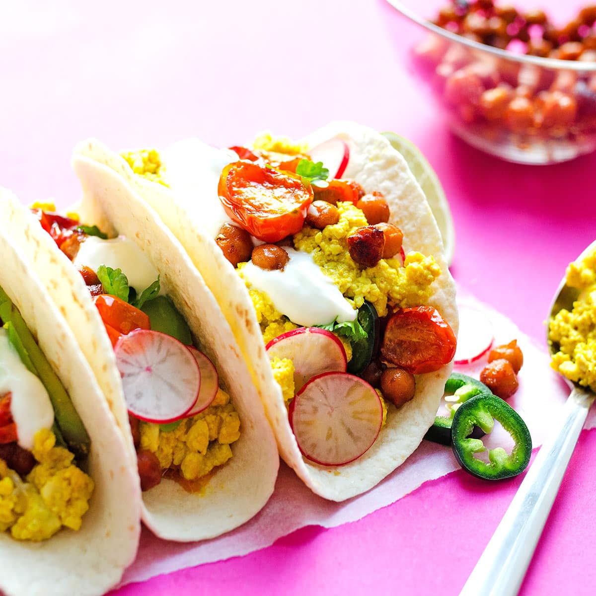 Picture of tofu scramble breakfast tacos on a pink background