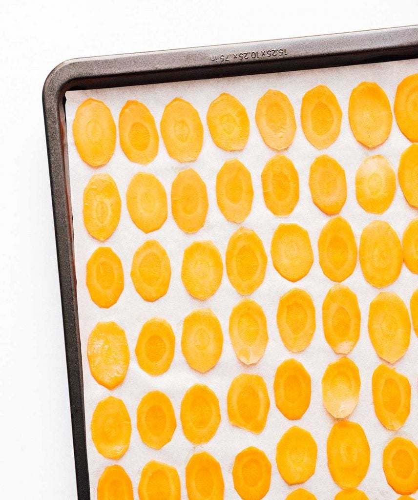 Carrot chips in a basket on a baking sheet white background