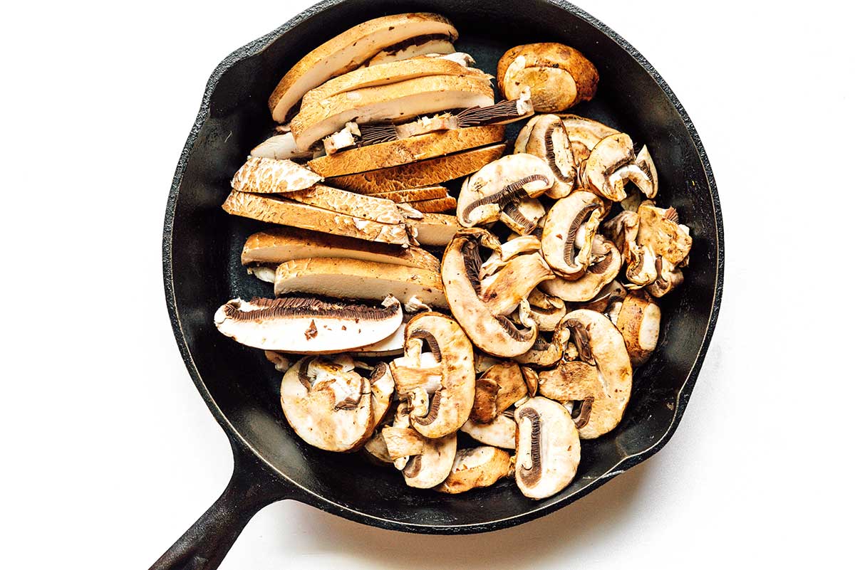 A cast iron skillet filled with sliced mushrooms.