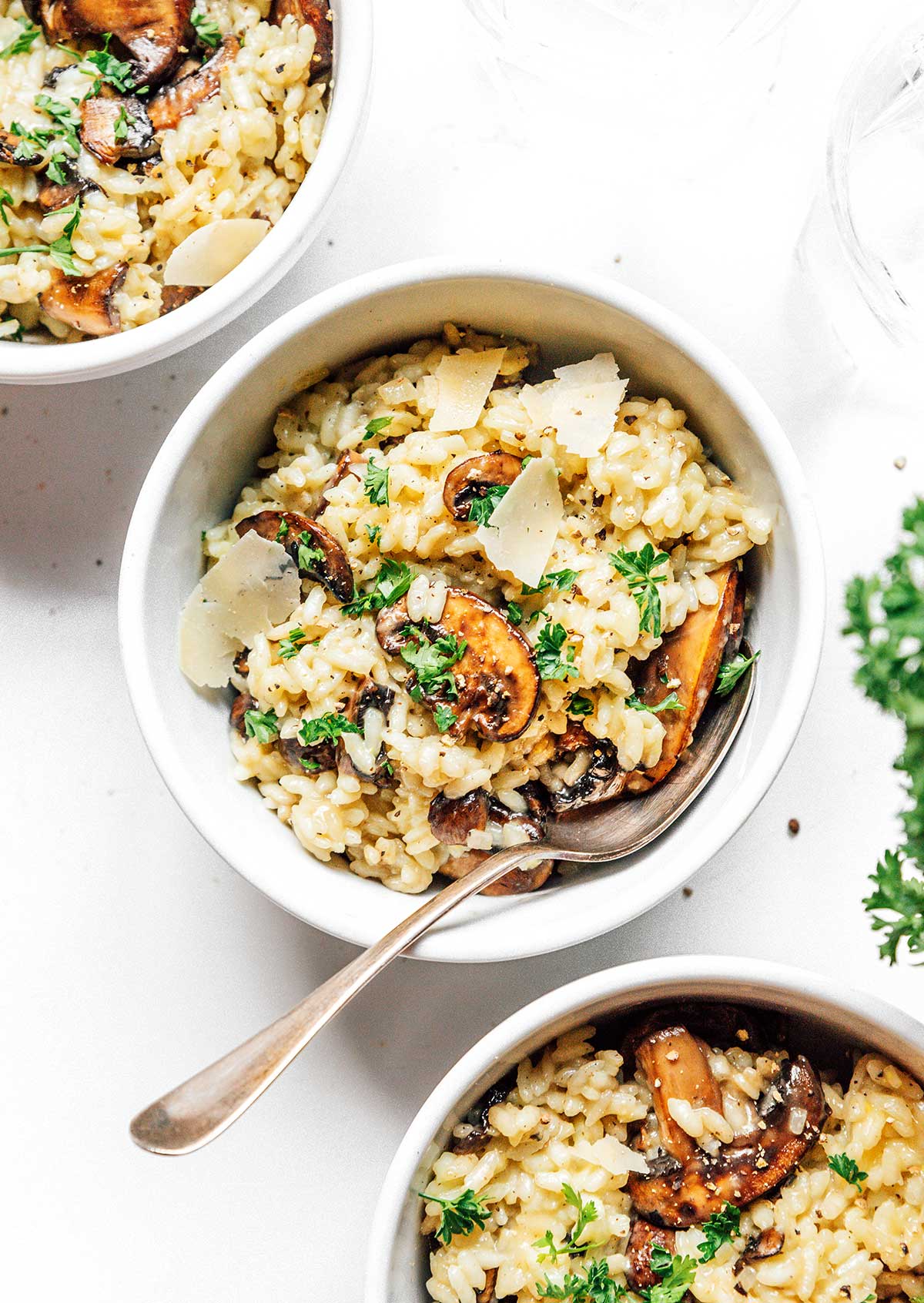 A white bowl filled with mushroom risotto and topped with parmesan flakes.