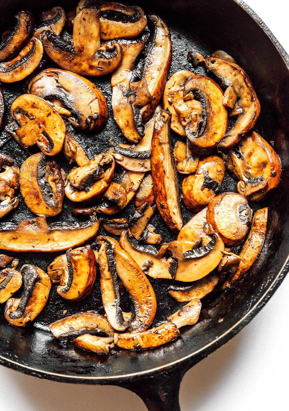 A cast iron skilled filled with cooked sliced mushrooms. 
