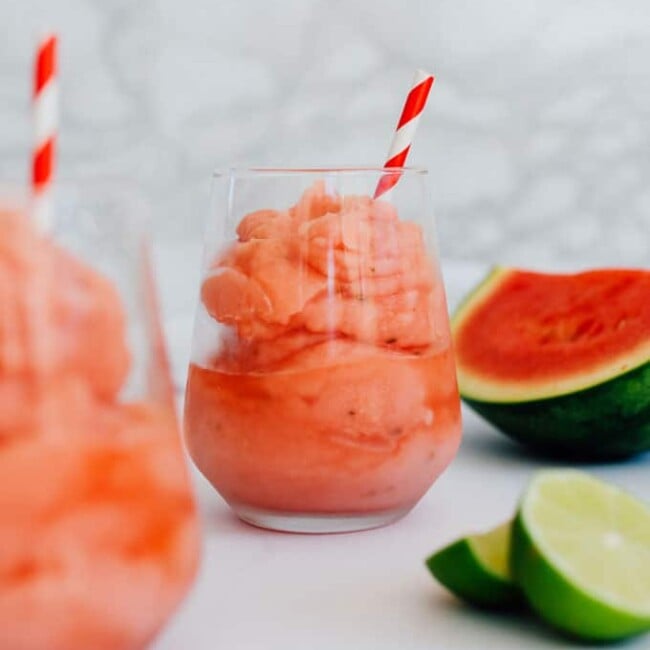 Watermelon pink slushy in clear glass with marble background - For when you’re craving a cocktail that can cool you off in the summer heat, this Frozen Watermelon Daiquiri is the answer, taking almost no time to prepare (and with just a handful of ingredients)!