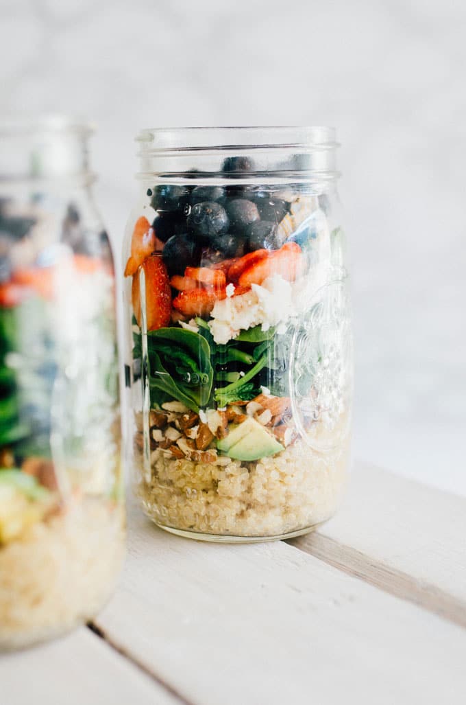 Layered salad in a mason jar with a white marble background - This 7-Layer Summer Berry Salad Jar is a filling and flavorful meal to-go that will get you excited for lunchtime!