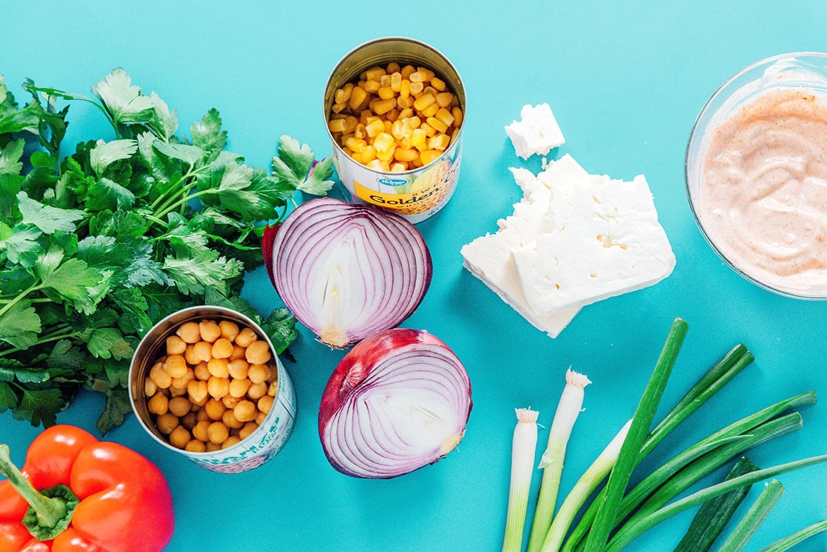 Ingredients for chickpea corn salad on a blue background.