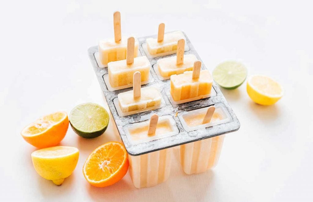 Popsicles in a mold with citrus fruit on a white background