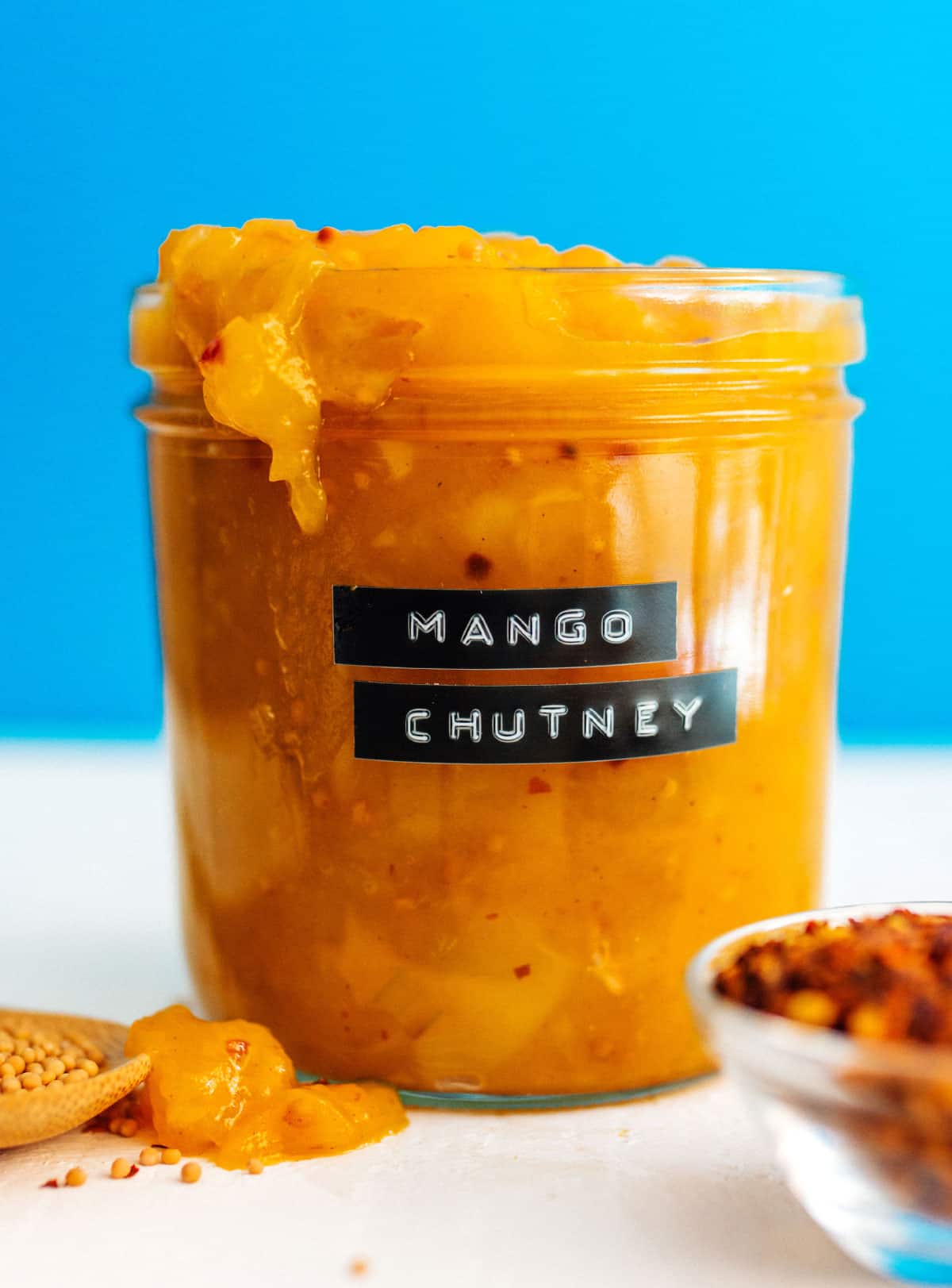 Labeled jar of mango chutney on a blue background