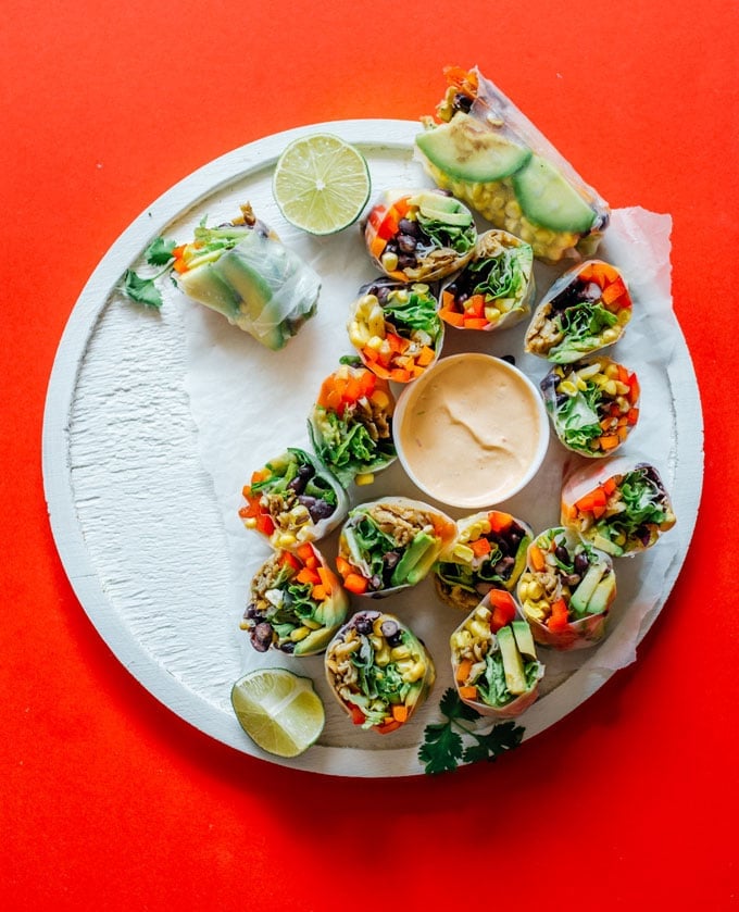 Spring rolls on red background white plate - These vegetarian Southwest Spring Rolls are packed with fresh vegetables and dipped in a smoky chipotle sauce. You’ll forget how healthy they are as you devour the whole pile!