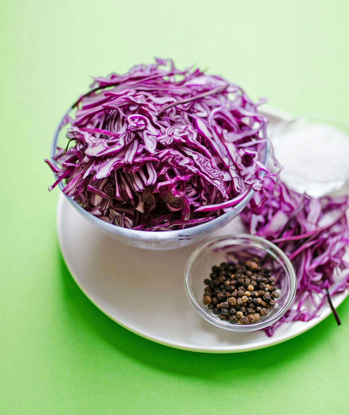 Red cabbage cut in half and shredded on a green background.