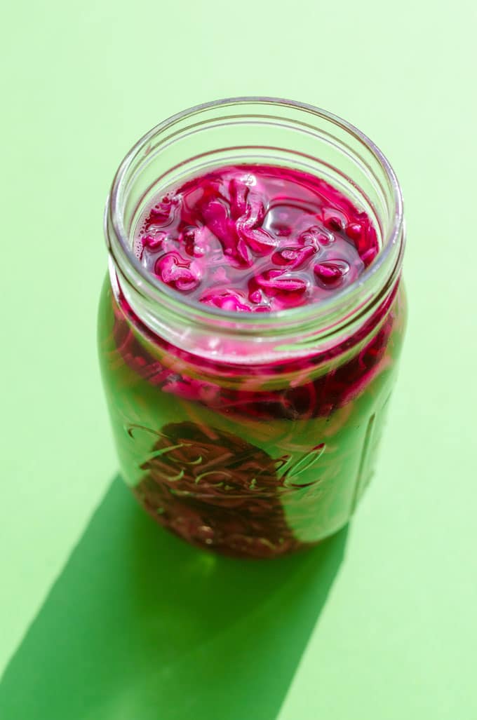 Pickled red cabbage in a mason jar on a green background