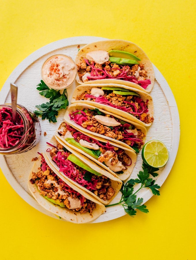 Soyrizo tacos with pickled red cabbage on a plate from overhead with a yellow background
