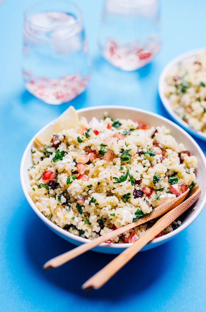 Bulgur salad with feta cheese, raisins, and pomegranate in a bowl on a blue background