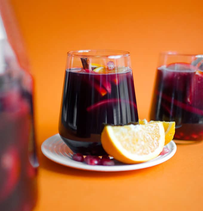Winter sangria in a wine glass on an orange background