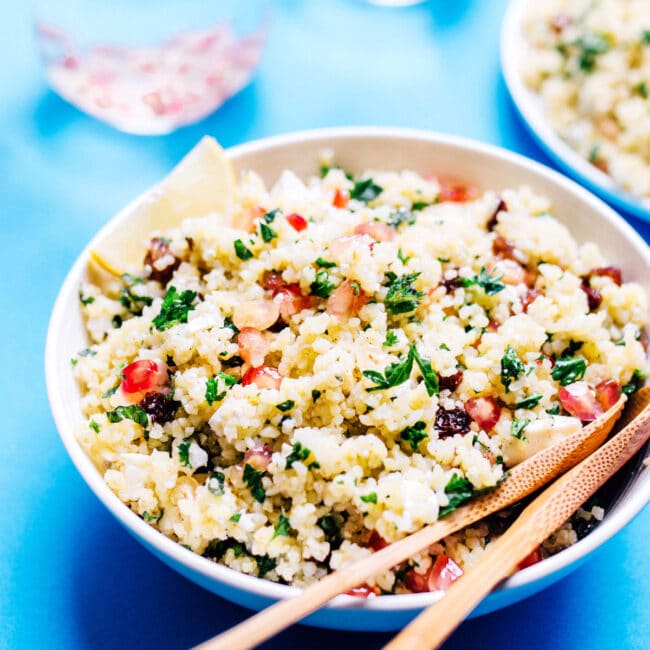 Bulgur salad with feta cheese, raisins, and pomegranate in a bowl on a blue background