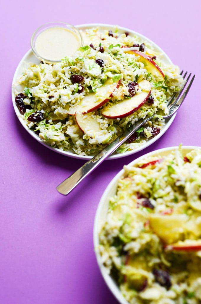 Shaved Brussels sprout salad with apples and cranberries on a purple background